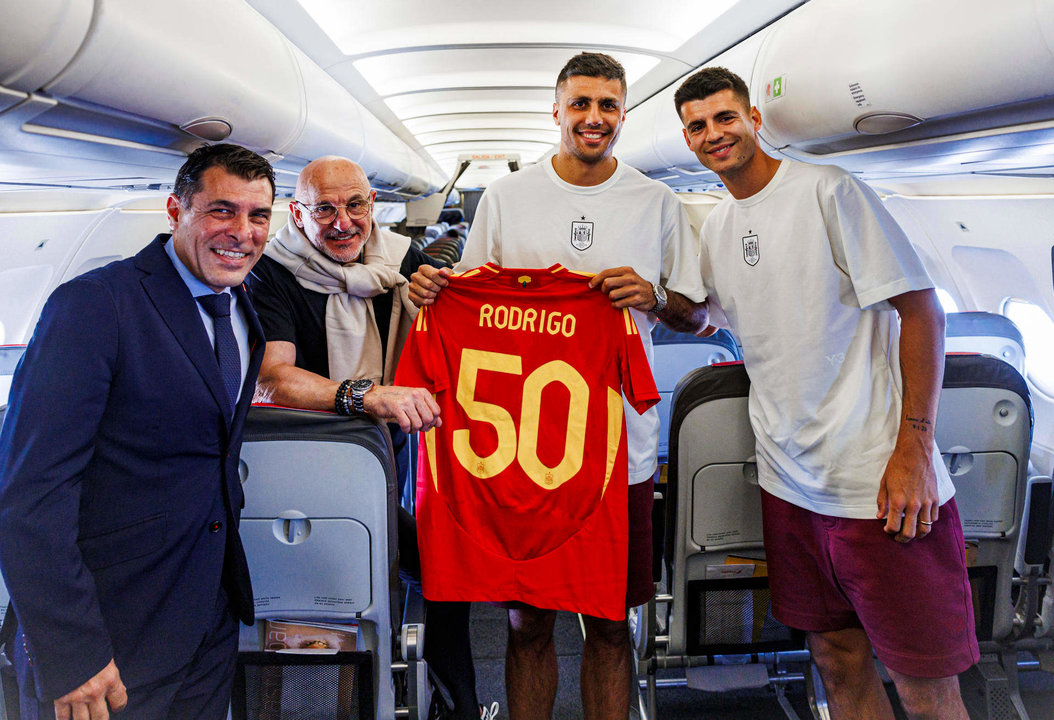 El centrocampista de la selección española Rodrigo Hernández 'Rodri' recibe una camiseta conmemorativa por sus 50 partidos como internacional y posa junto al capitán del equipo, Álvaro Morata (d), el seleccionador, Luis de la Fuente (2-i), y el vicepresidente de la Real Federación Española de Fútbol (RFEF), Alejandro Morales Mansito (i), en el aeropuerto de Palma de Mallorca, antes de poner rumbo a Alemania, donde la selección española disputará la Eurocopa 2024. "Cumplí el sueño más importante que he tenido desde pequeño, jugar con la selección de mi país", recuerda Rodri. "El fútbol y la vida pasan muy rápido, detrás de los 50 partidos hay muchos recuerdos dulces y otros no tanto, he jugado un Mundial, una Eurocopa y un Nations League pero si me tengo que quedar con un momento, sería el día de mi debut", eligió. EFE/RFEF/Pablo García